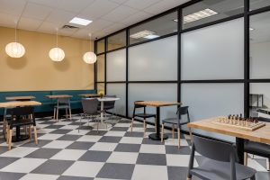 The cafe has white and black checkered tile floor and many seating areas.