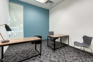 A medium sized private office with two wooden desks and chairs.