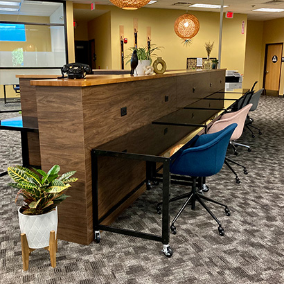 Coworking space shows beautiful wooden divider with several desks and seats. Green plants decorate the space.