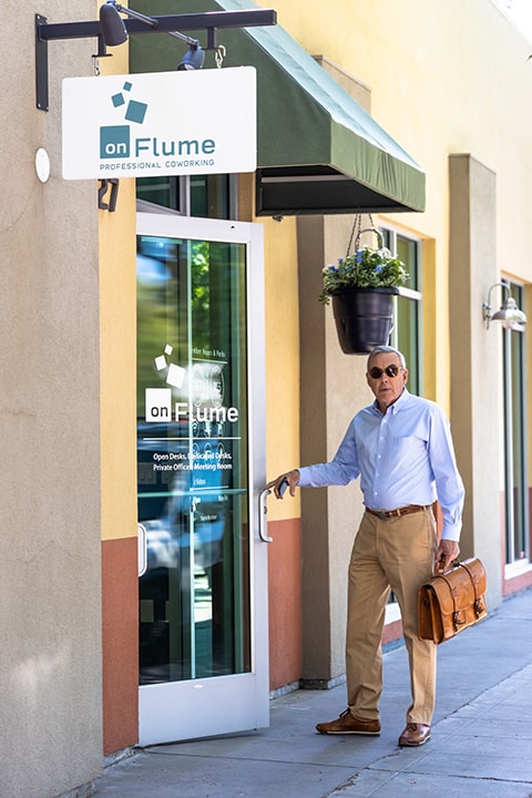 Businessman opening the door to onflume shows the signage for the business.