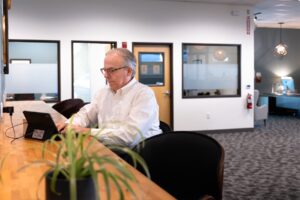 A man uses his laptop at a wooden bar in our open coworking space.