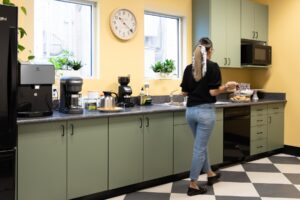 A woman entering the kitchen to get free coffee at onflume.