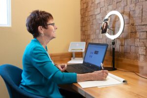 A woman in a teal sweater uses onflume's phone booth to make a video call to a colleague.