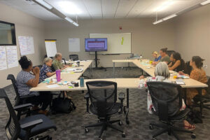 People sitting around a table and watching a screen
